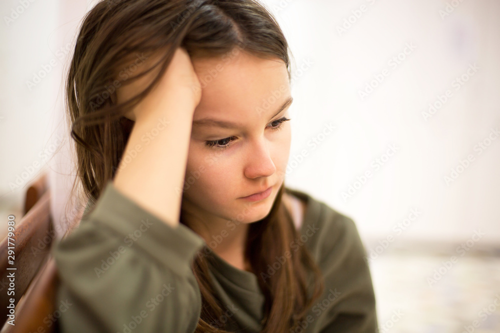 Unhappy depressed teenager with face in hands sitting on the bench Unhappy depressed teenager with face in hands sitting on the bench