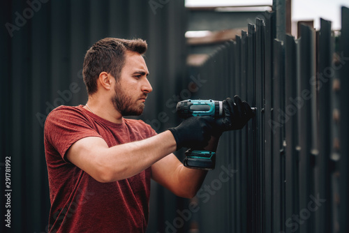 Construction worker using screwdriver for fastening and drilling screws photo