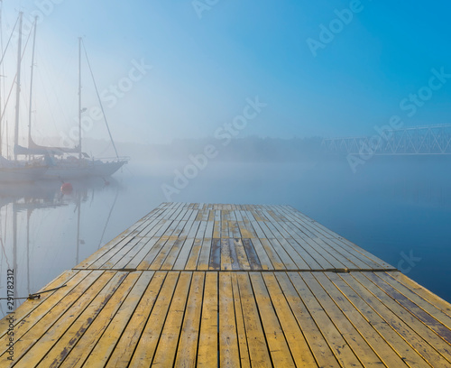 Autumnal mist on a river with sail boats and yachts  anchored in harbor,  at ...