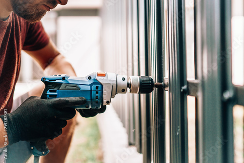 Man working with an electric screwdriver on the construction site photo