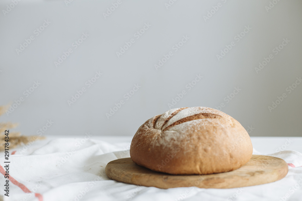 Loaf of bread on a board on a white tablecloth Loaf of bread on a board on a white tablecloth