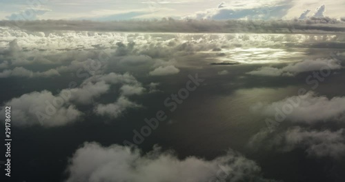 Airplane flies over ocean clouds, wide aerial