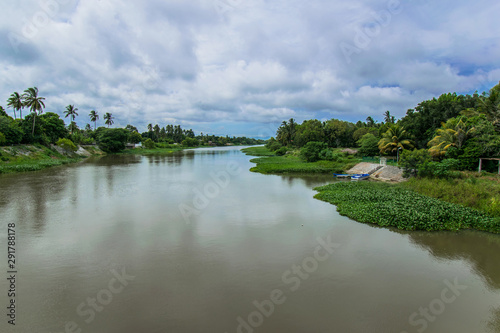 tropical river entering  the ocean with blue sky and tropical plants © Jorge
