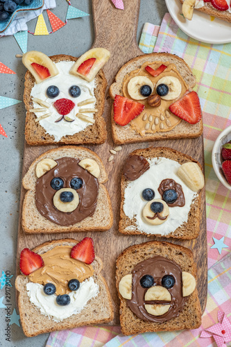 Funny animal faces toasts with spreads, butters, banana, strawberry and blueberry