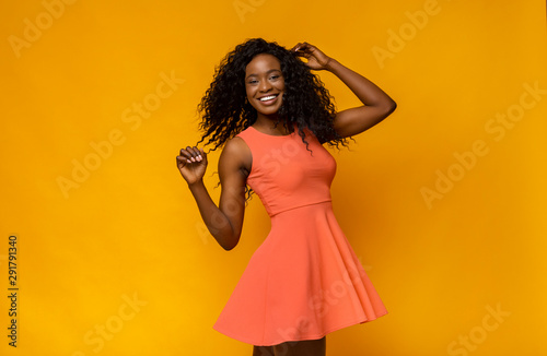 Joyful african girl in summer dress turning around photo