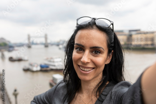 Portrait of awoman taking a selfie in the city with Tower Bridge on background, London, UK photo