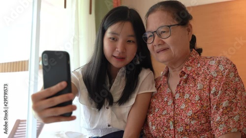 Asian grandmother and her niece having fun with using smartphone and taking selfie together, family concept