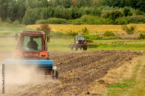 HomA tractor rips the ground in a dusty field.emade goat in the pasture.