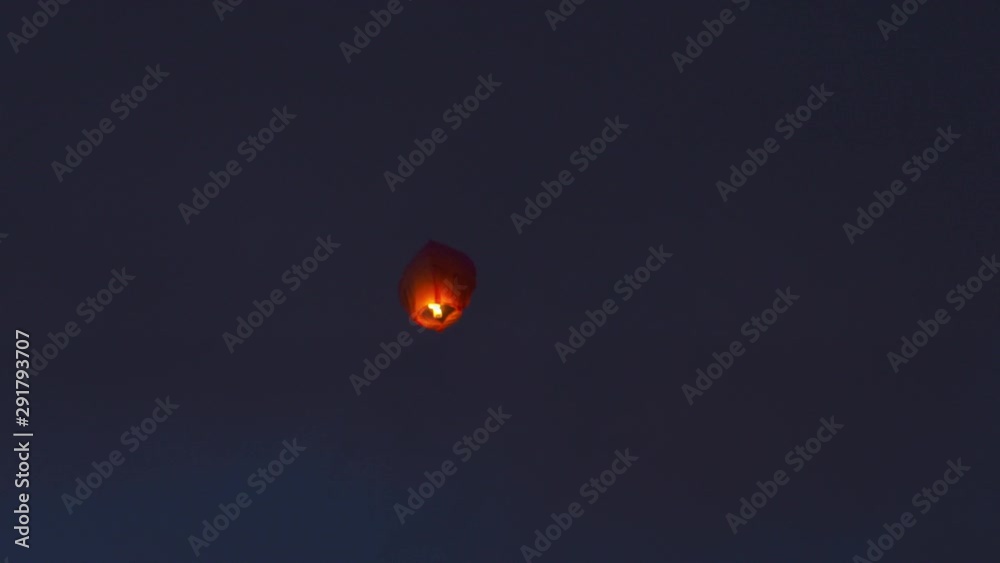 A nighttime closeup shot of an illuminated Chinese lantern, also known as Kongming lantern or sky lantern, floating up into the dark sky. A nighttime closeup shot of an illuminated Chinese lantern, also known as Kongming lantern or sky lantern, floating up into the dark sky.