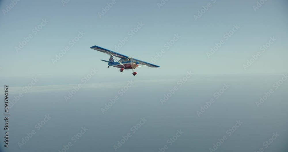 Foggy helicopter aerial of small seaplane flying above ocean, day