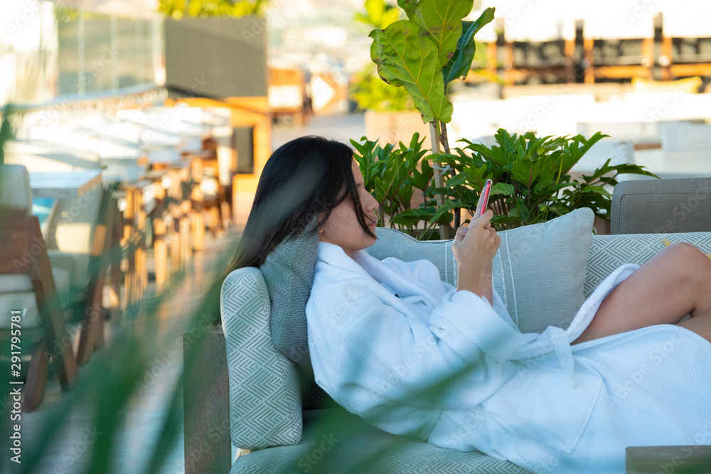 Obraz premium girl lying on the couch using cellphone in the balcony