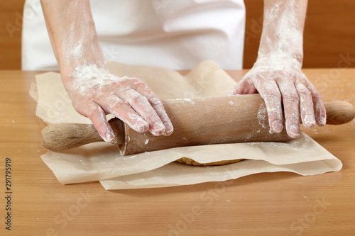 A baker rolling a dough between sheets of baking paper. Making Pastry Dough for Hungarian Cake. Series.