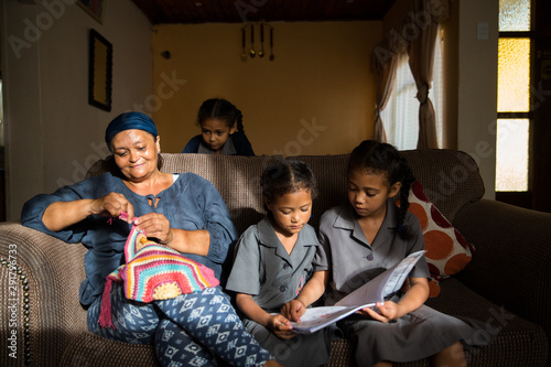 Mother crochetsing whilst her daughters do school work