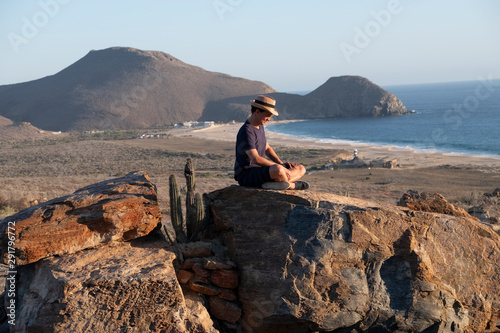man sitting on a rock with head down on the sunset thinking and
