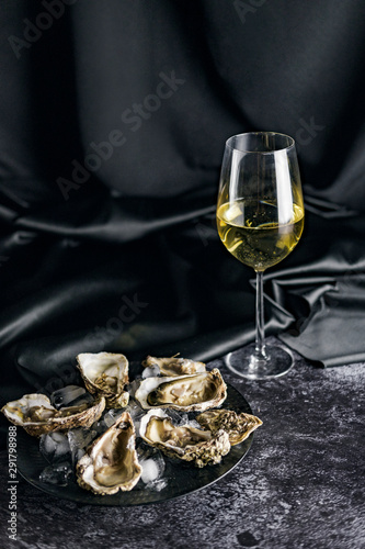 Opened oysters and white wine on stone table