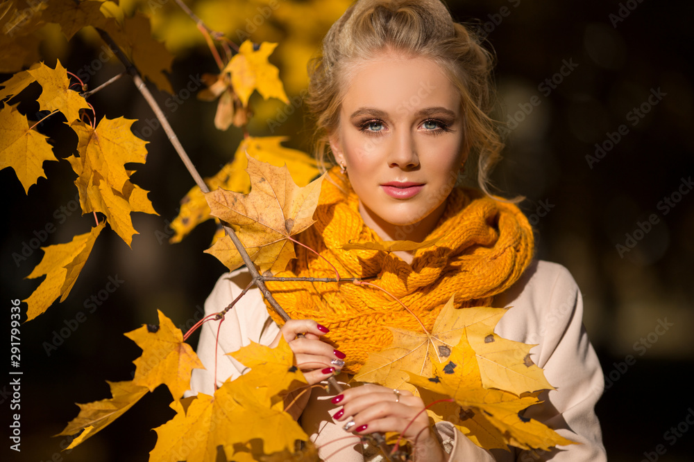 Portrait of pretty blonde teen girl with fashion makeup near autumn tree with yellow leaves