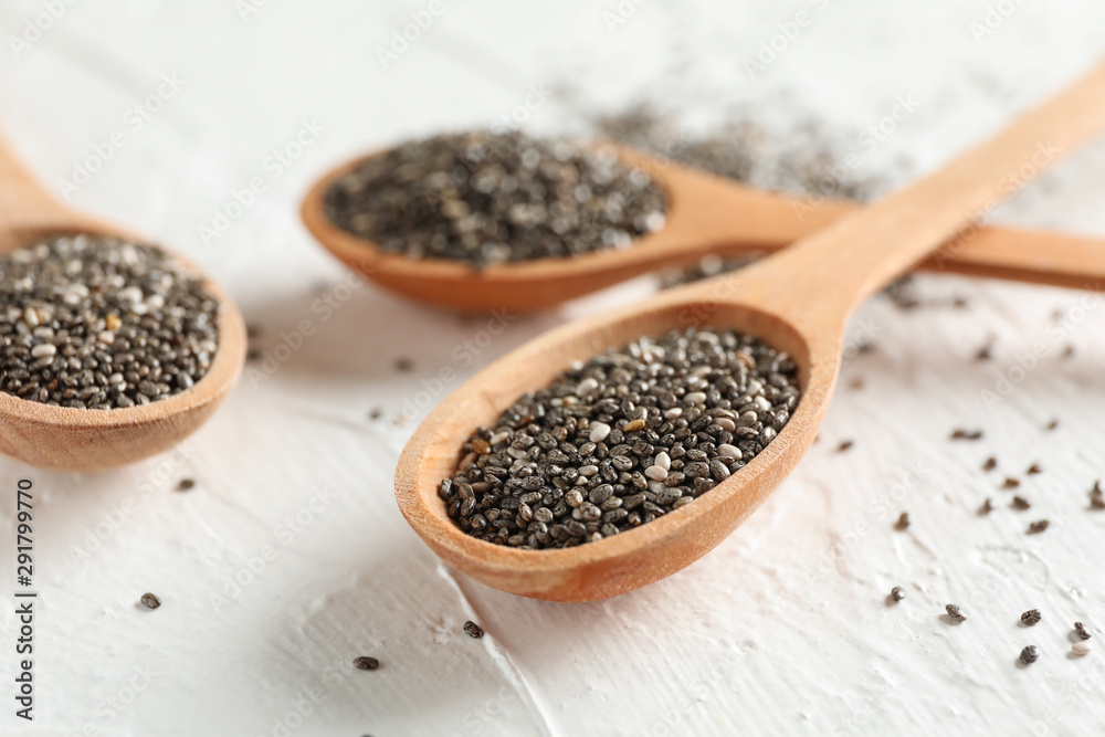 Wooden spoons and chia on white background, close up Wooden spoons and chia on white background, close up
