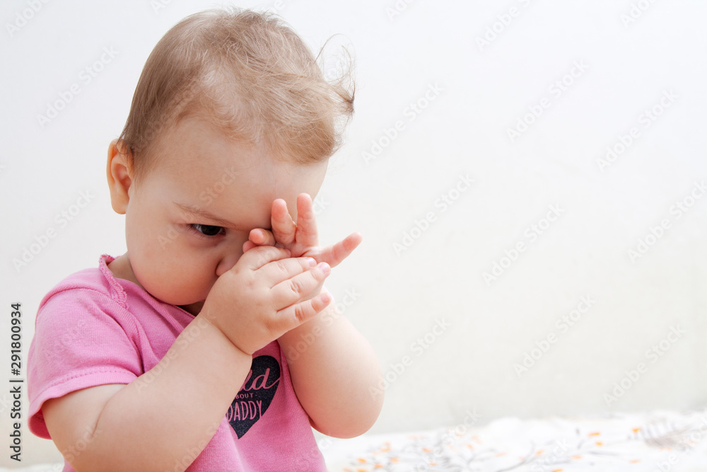 A small child rubs his eyes - an infant is tired and wants to sleep A small child rubs his eyes - an infant is tired and wants to sleep