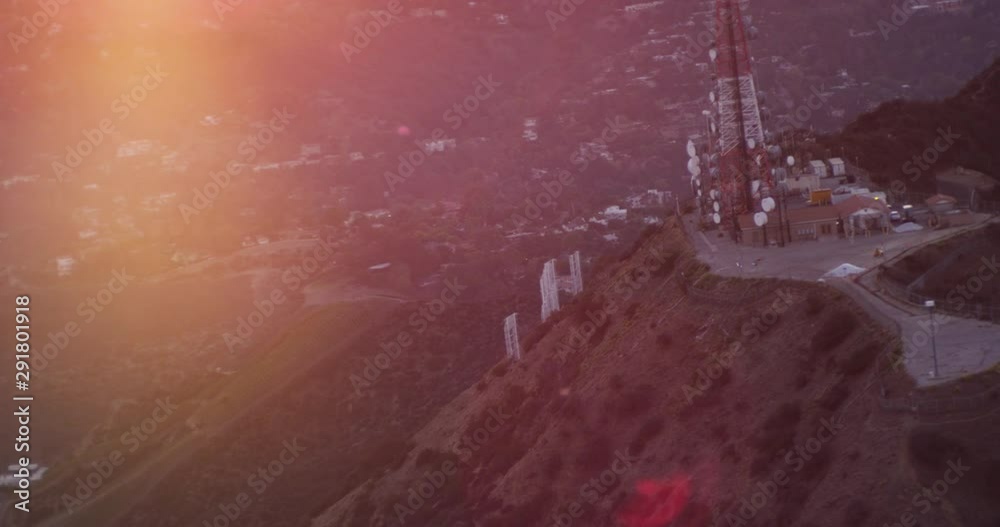 Helicopter aerial shot rotating around cellphone tower on Hollywood Hills, sunset