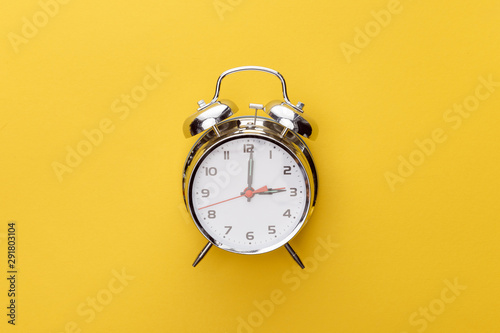 top view metal clock on yellow background