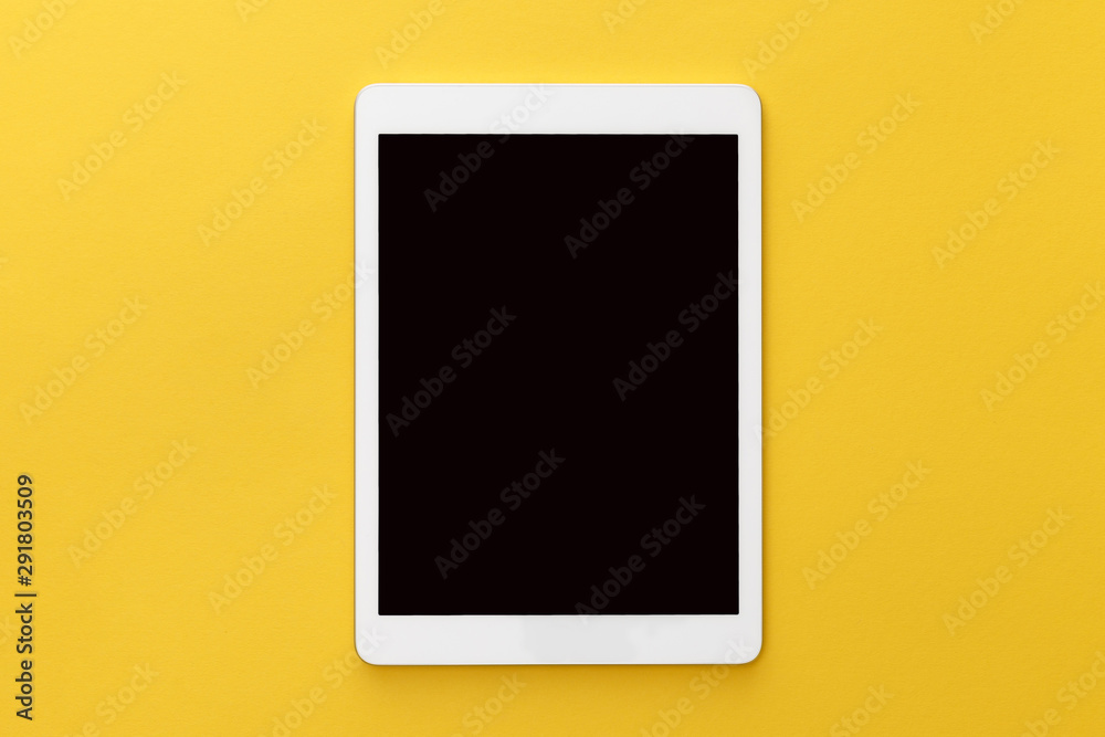 top view of digital tablet with blank screen on yellow background