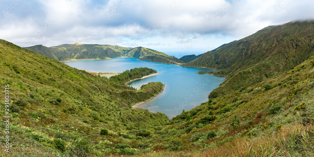 Panoramic view of Lagoa do Fogo, a crater lake on the island of São Miguel in the Azores archipelago.  The blue lagoon is in the central caldera of the Água de Pau Massif, pictured under a cloudy sky.