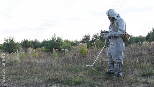 Military in a protective suit checks the level of radiation on the road dosimeter, radiation hazard, military dosimetrists photo