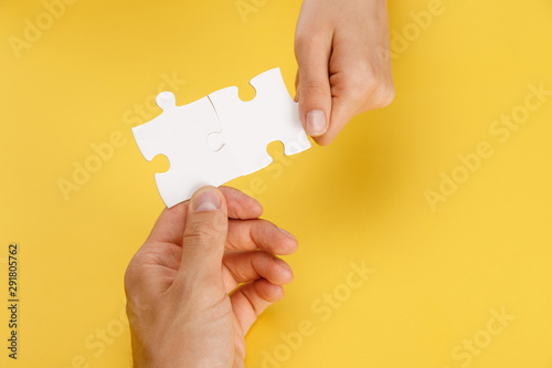 cropped view of man and woman holding pieces of white puzzle on yellow background