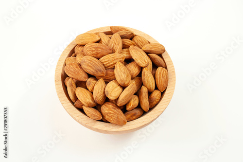 Almonds in a wood bowl on white background © Monika