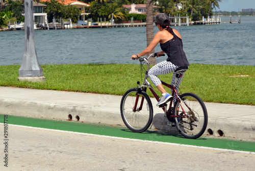 Woman riding a bicycle across the Venetia Causeway in Miami Beach,Florida with RivoAlto island in the background photo