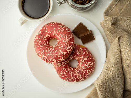 Pączki z różową polewą, kawa w filiżance. Widok z góry.