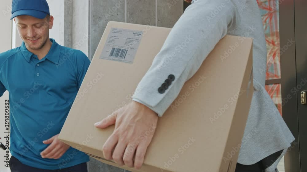 Delivery Man Gives Postal Package to a Business Customer, Who Signs Electronic Signature POD Device. In Stylish Modern Urban Office Area Courier Delivers Cardboard Box Parcel to a Man. Slow Motion