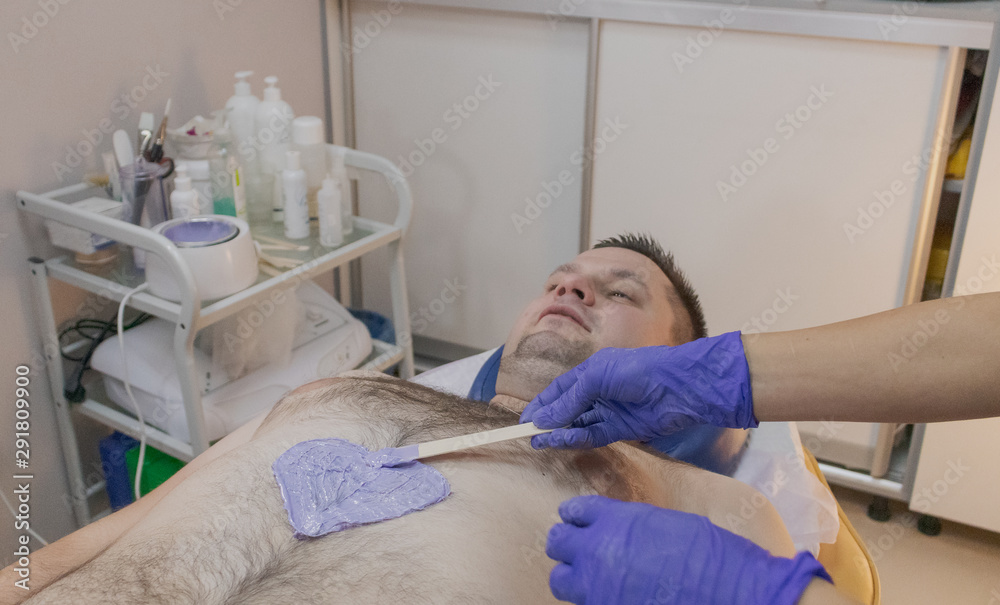Handsome man on waxing procedure in a beauty salon.