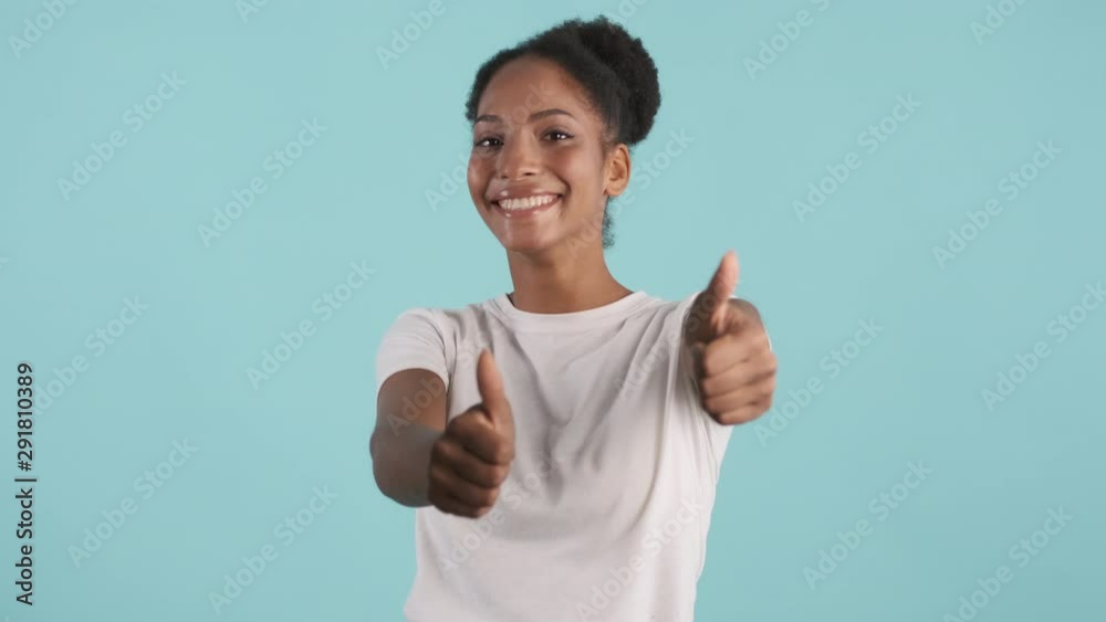Portrait of cheerful african american girl joyfully showing thumbs up gesture on camera over blue background