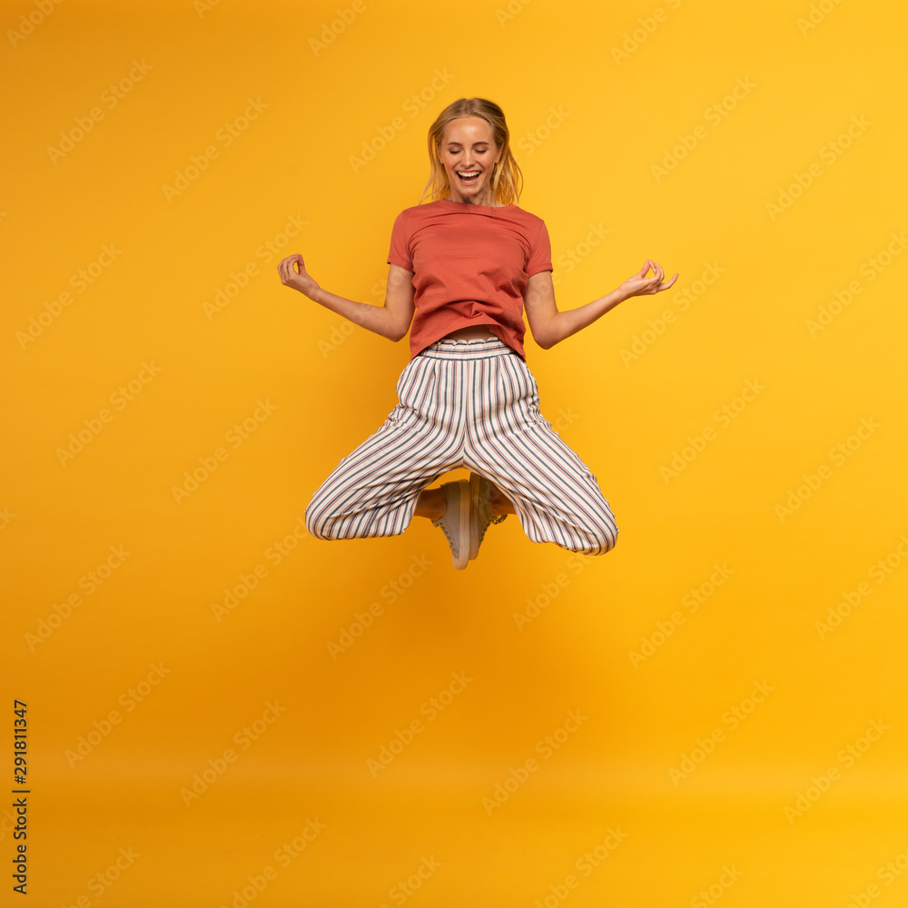 Blonde girl jumps in yogas position. Relax concept. Yellow background - obrazy, fototapety, plakaty 