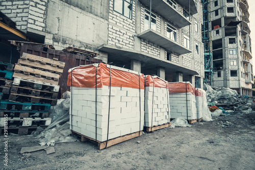Pallets of white blocks or cinder blocks at construction site of new modern building, close up