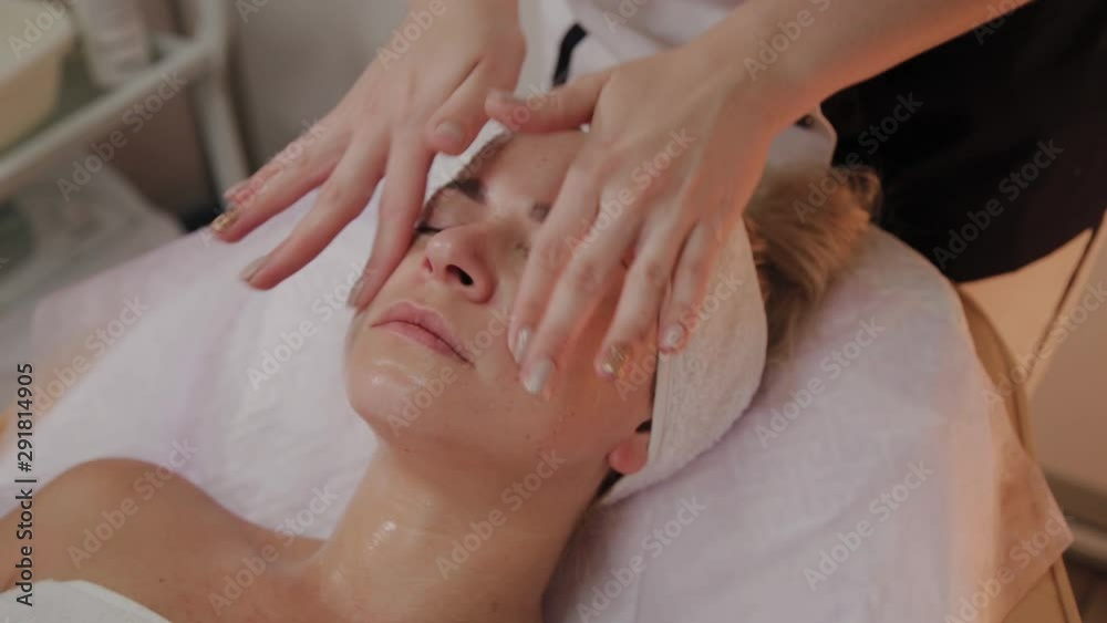 Spa woman facial Massage. Face Massage in beauty spa salon. Female enjoying relaxing face massage in cosmetology spa centre. Body care, skin care, wellness, beauty treatment. Spa woman facial Massage. Face Massage in beauty spa salon. Female enjoying relaxing face massage in cosmetology spa centre. Body care, skin care, wellness, beauty treatment.
