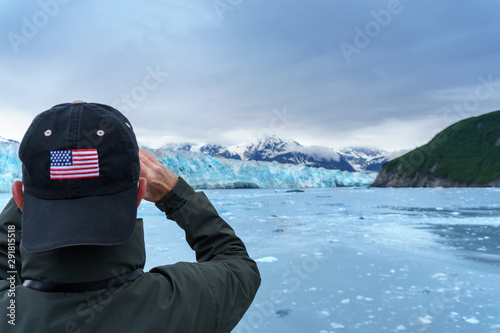 Man in hat with USA flag is taking a photo of a Hubbard Glacier. He is on a cruise in Alaska. Expedition to the glaciers photo
