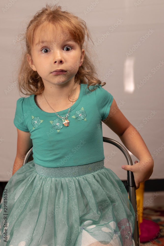 Young girl in teal dress looking surprised
