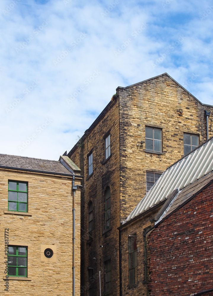 old 19th century stone warehouse and factory buildings in bradford west yorkshire against a blue cloudy sky old 19th century stone warehouse and factory buildings in bradford west yorkshire against a blue cloudy sky
