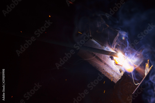 Arc welding. Welding of two sheets of metal by electrode in inert gases. Type MMA. A bright flash of light and a sheaf of sparks in a cloud of smoke. Miniature Universe. Free space for inscriptions.