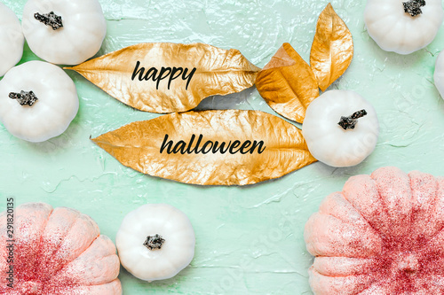 Pink and white pumpkins with glitter and gold leaves on neo mint background, creative concept. Festive advertising flat lay banner. Halloween decor celebration. Trendy composition color, copy space photo