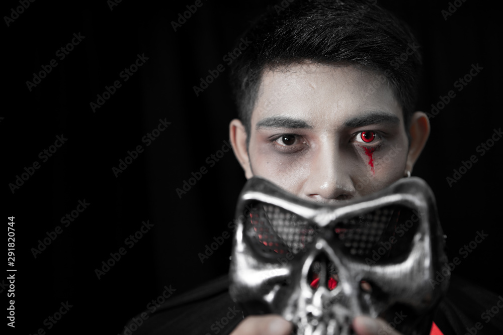 Asian man dressed as a ghost and skull mask handles coming off the face itself. Asian man dressed as a ghost and skull mask handles coming off the face itself.
