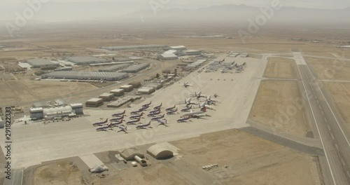 Aerials hot, day, high altitude view of runway and planes parked in lot, drone