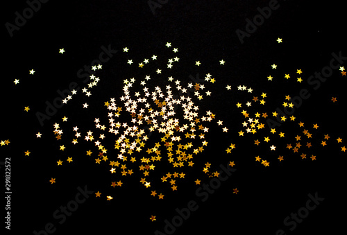 Sparkling background of glowing golden stars against black
