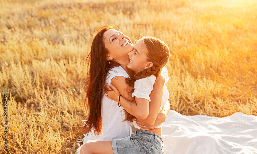 Mother and daughter hugging and smiling in warm sun light on white blanket Mother and daughter hugging and smiling in warm sun light on white blanket