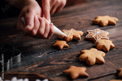 Christmas and New Year celebration traditions. Family cooking, traditional sweets. Decorating gingerbread cookie with confectionery icing, close up