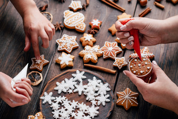Christmas and New Year celebration traditions, festive sweets, family culinary. Traditional gingerbread. Friends decorating freshly baked cookies with icing and mastic