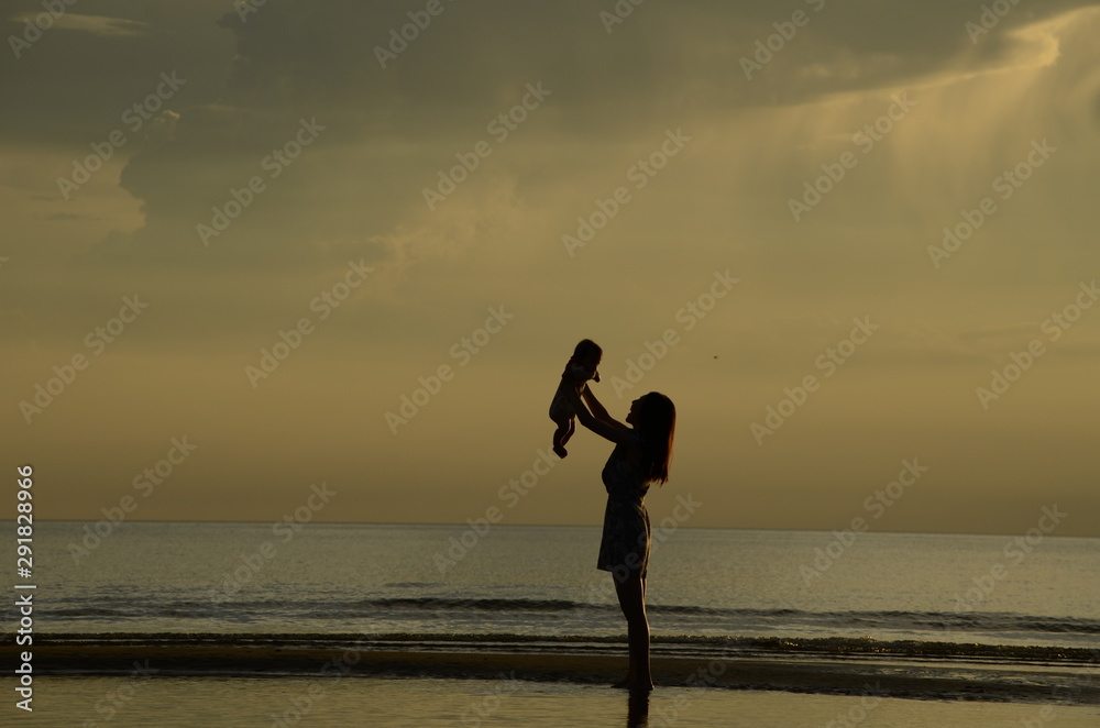Fototapeta premium silhouette of mother and baby on the beach at sunset