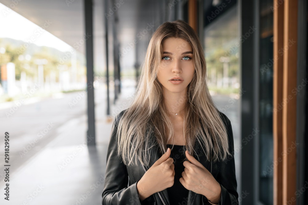 Portrait of a charming blonde with blue eyes in a black leather jacket with a decoration on her neck Portrait of a charming blonde with blue eyes in a black leather jacket with a decoration on her neck